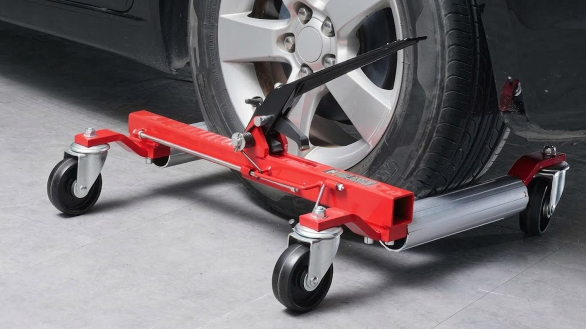 A red and silver car jack stand positioned under a vehicle wheel on a gray floor.